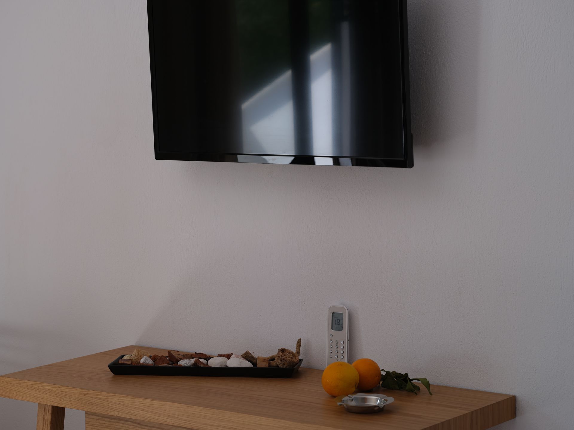 A flat screen tv is mounted to the wall above a wooden table