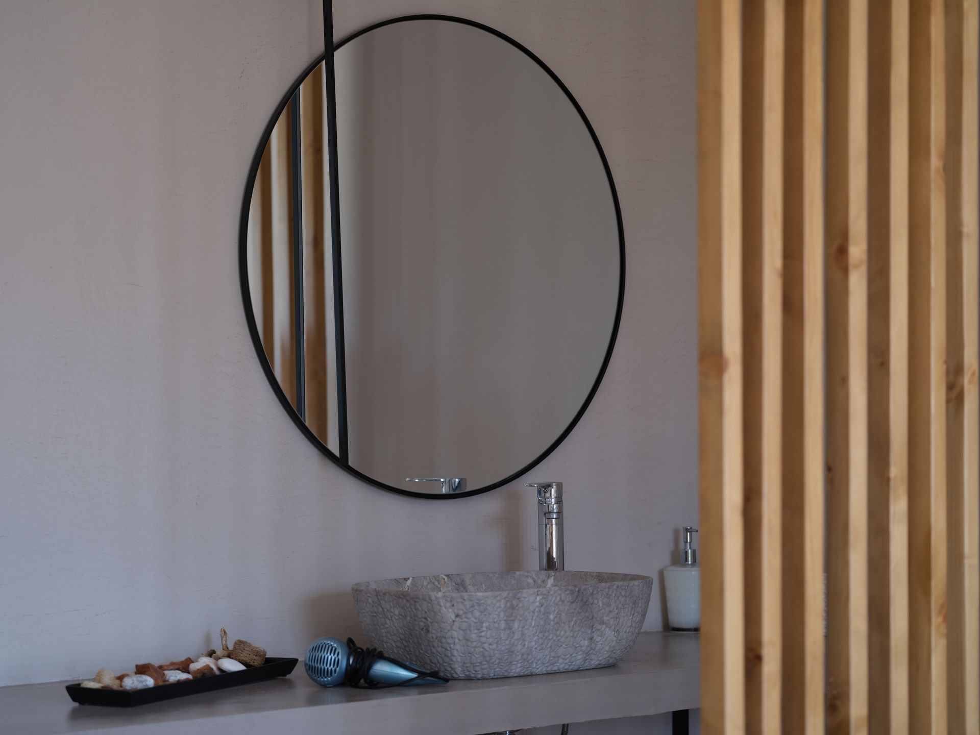 A bathroom with a round mirror and a sink