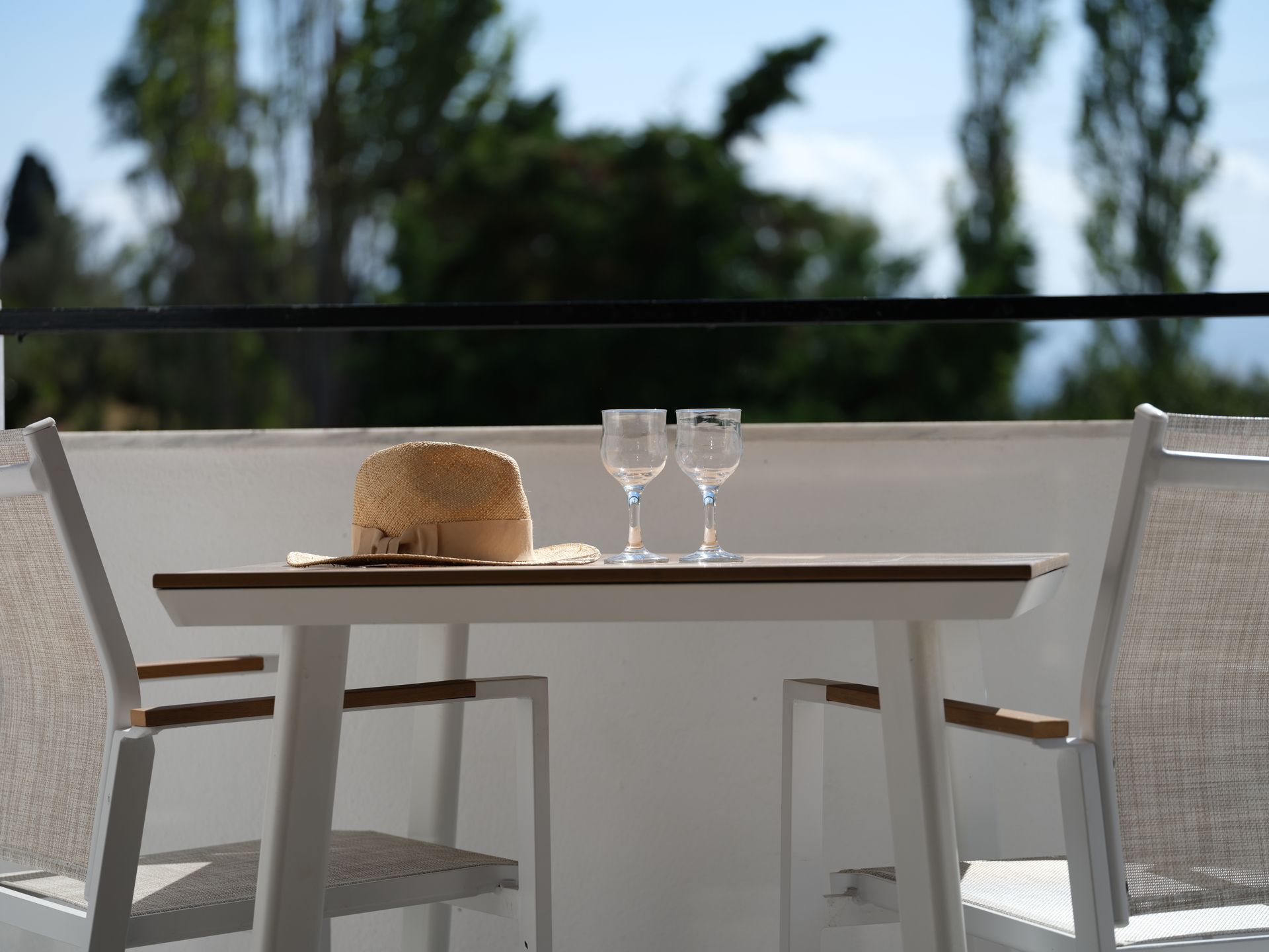 A table with two wine glasses and a hat on it