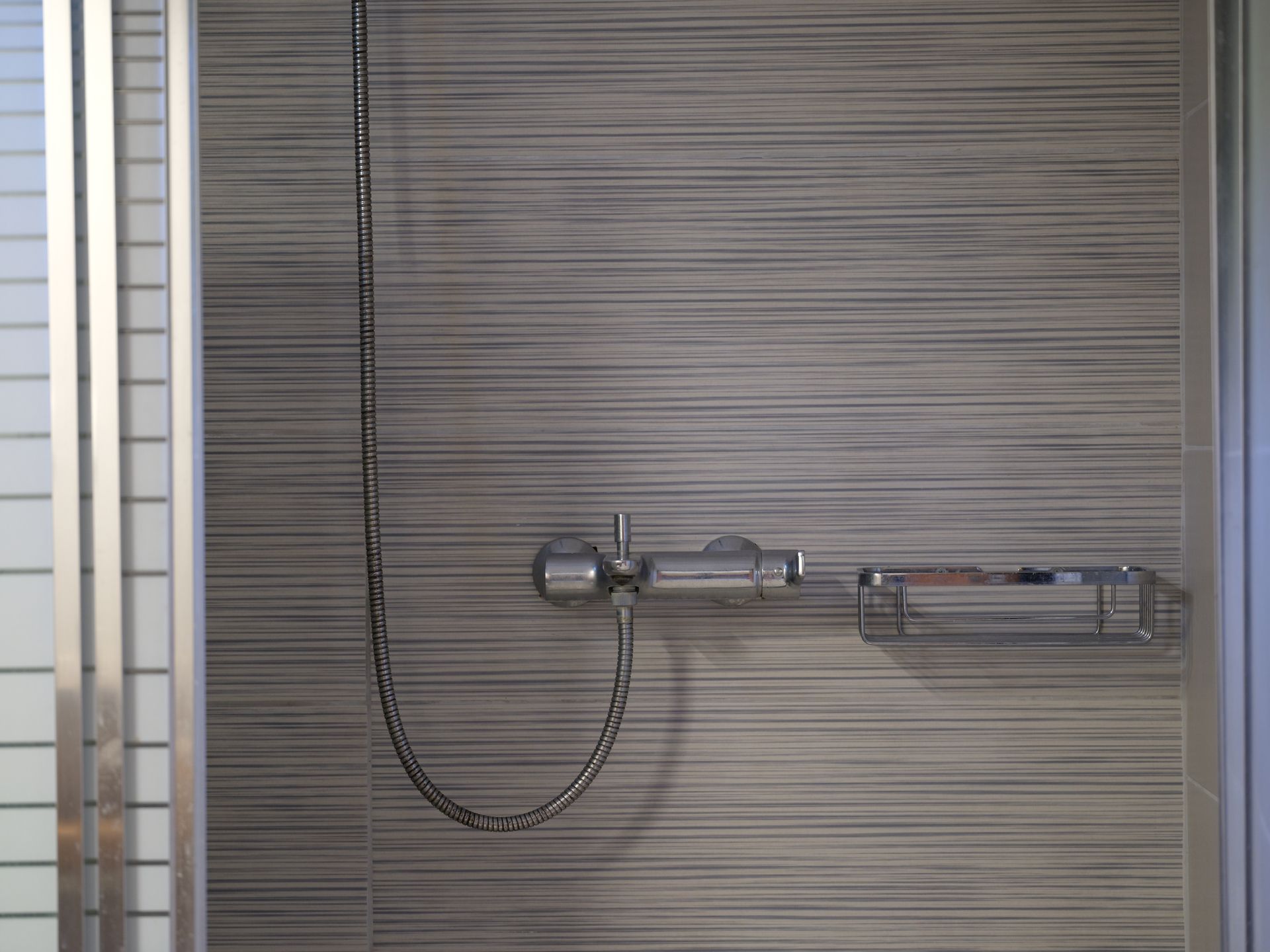 A shower stall with a shower head and a shelf.