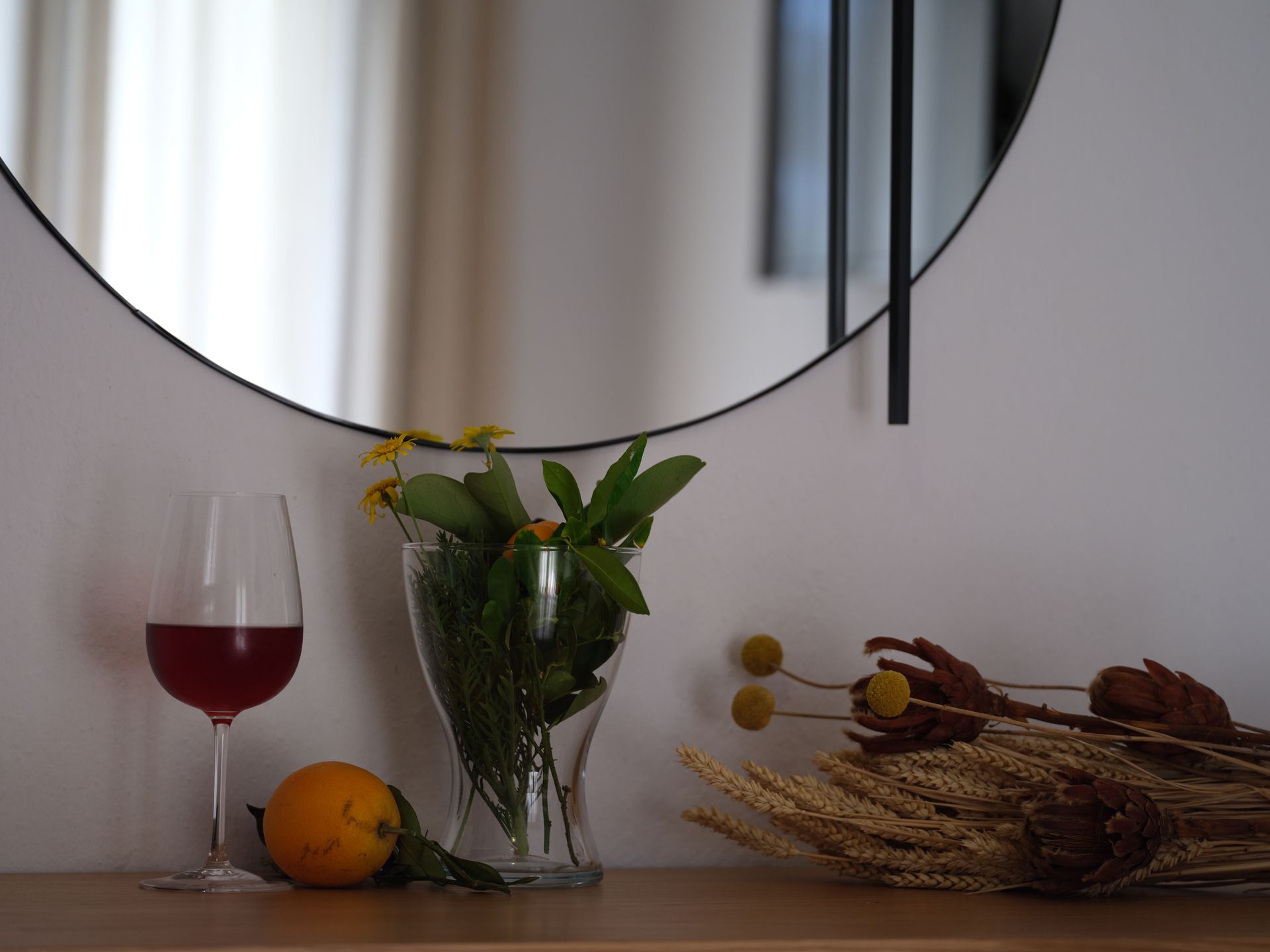 A table with a vase of flowers and a glass of wine