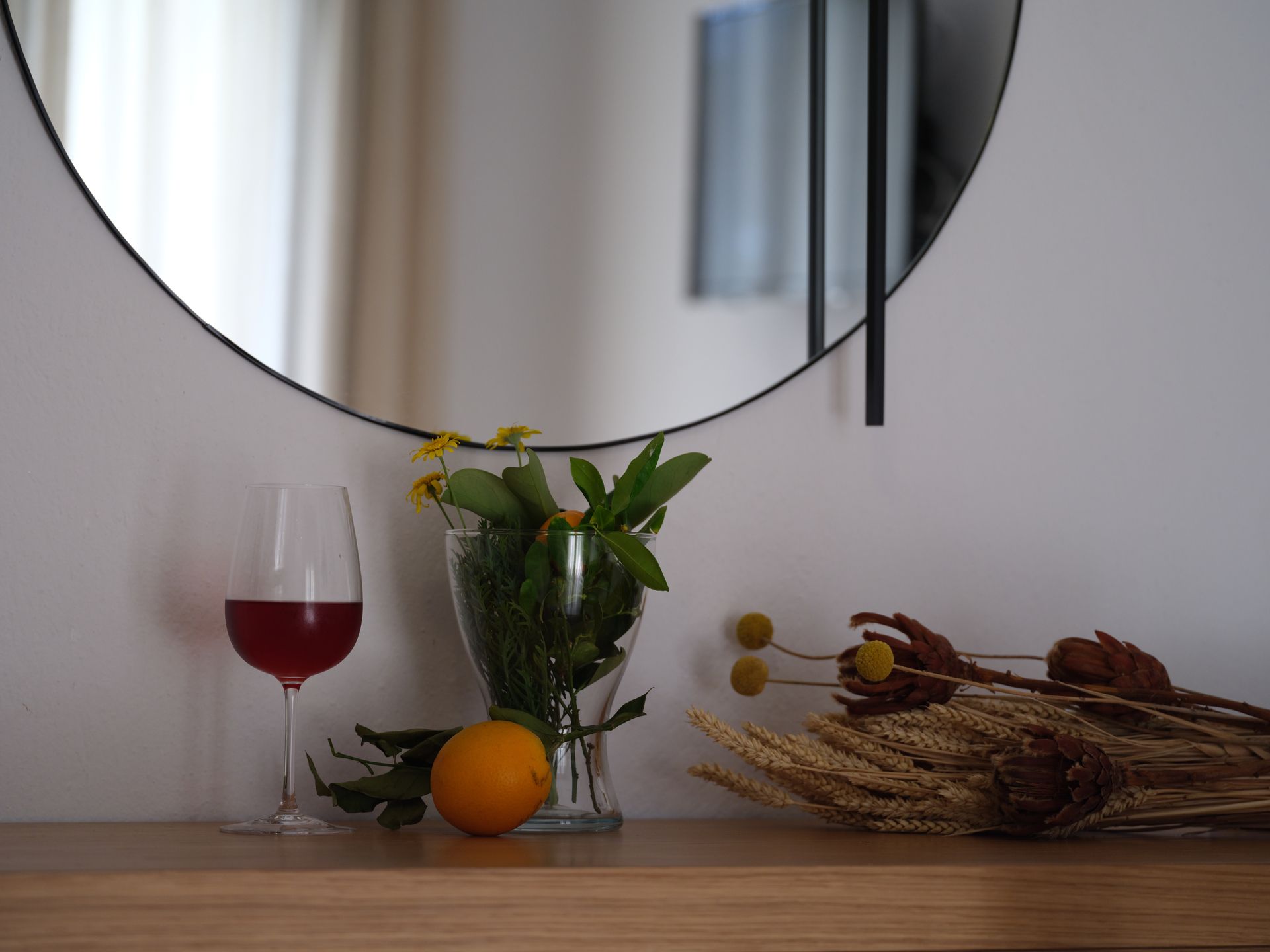 A table with a vase of flowers and a glass of wine