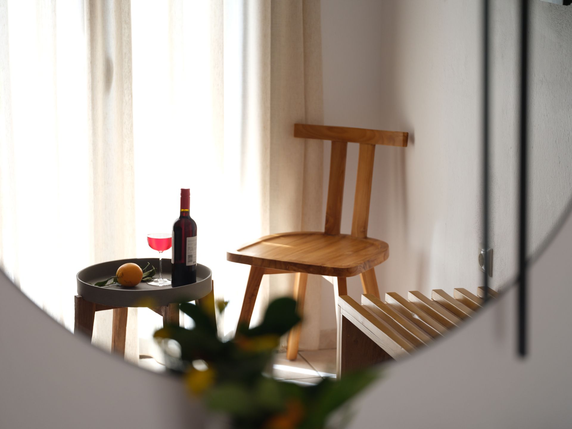 A bottle of wine is on a table next to a chair.