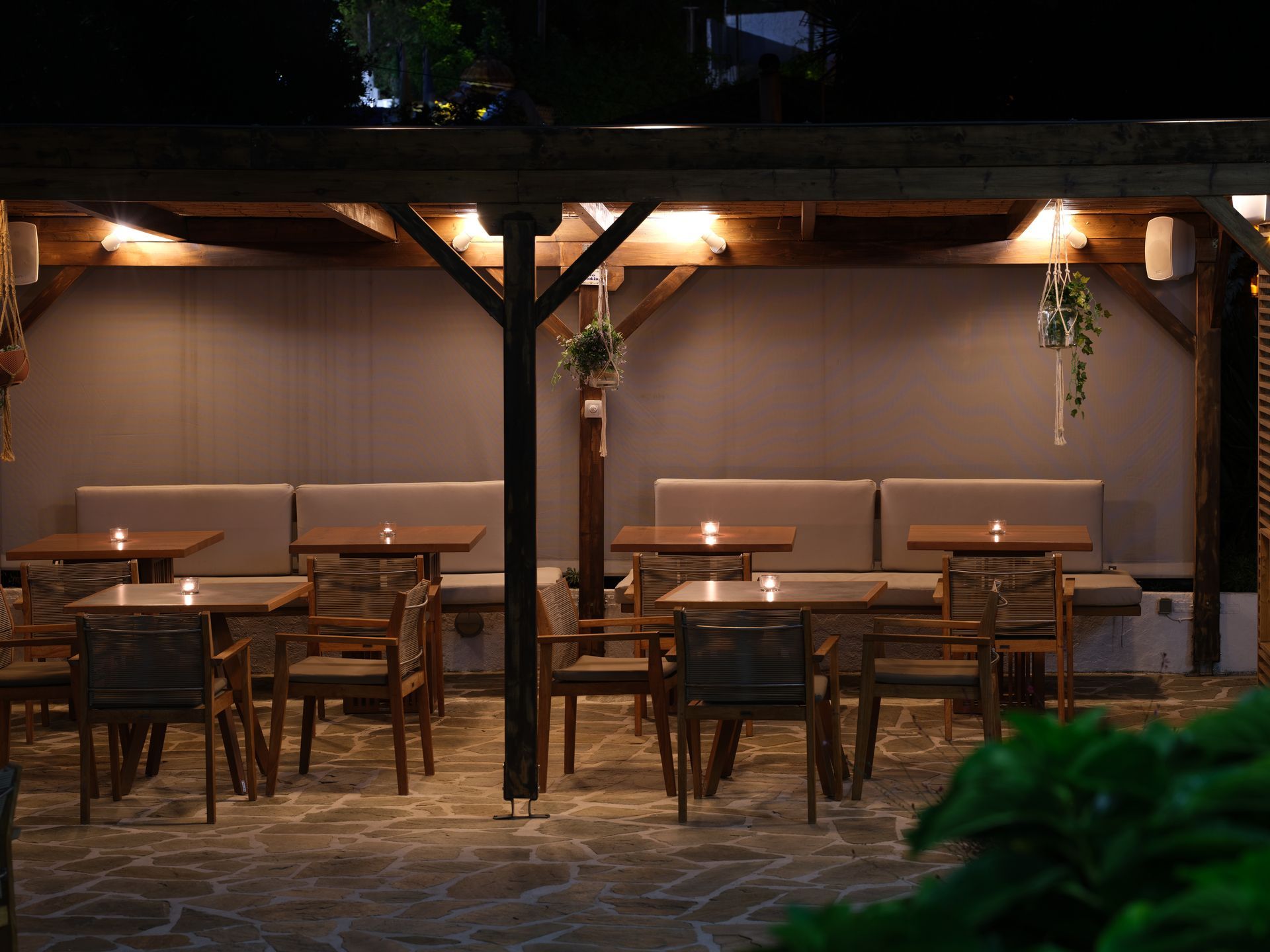 A restaurant with tables and chairs under a canopy at night.