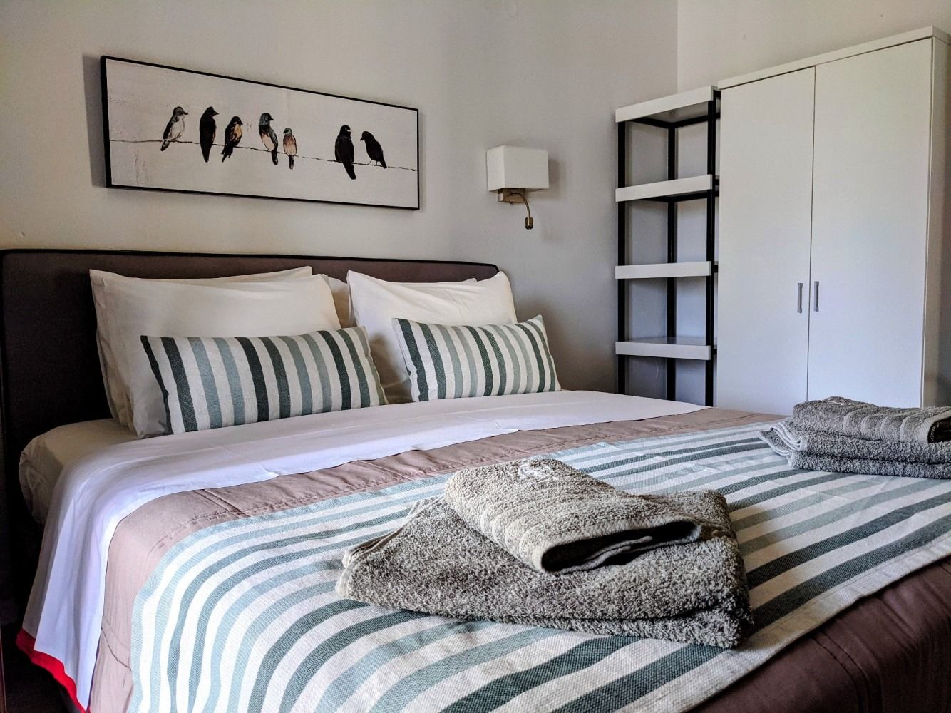 A bed with a striped comforter and pillows in a bedroom.
