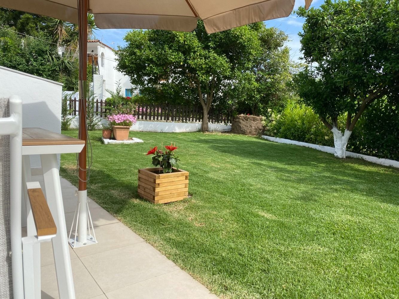 A large lush green lawn with a wooden planter in the middle of it.