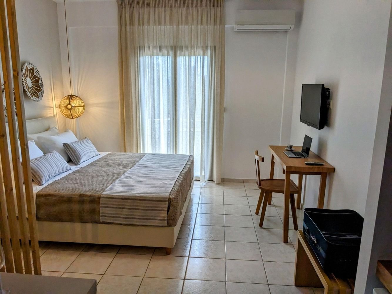 A hotel room with a bed , desk , chair and television.