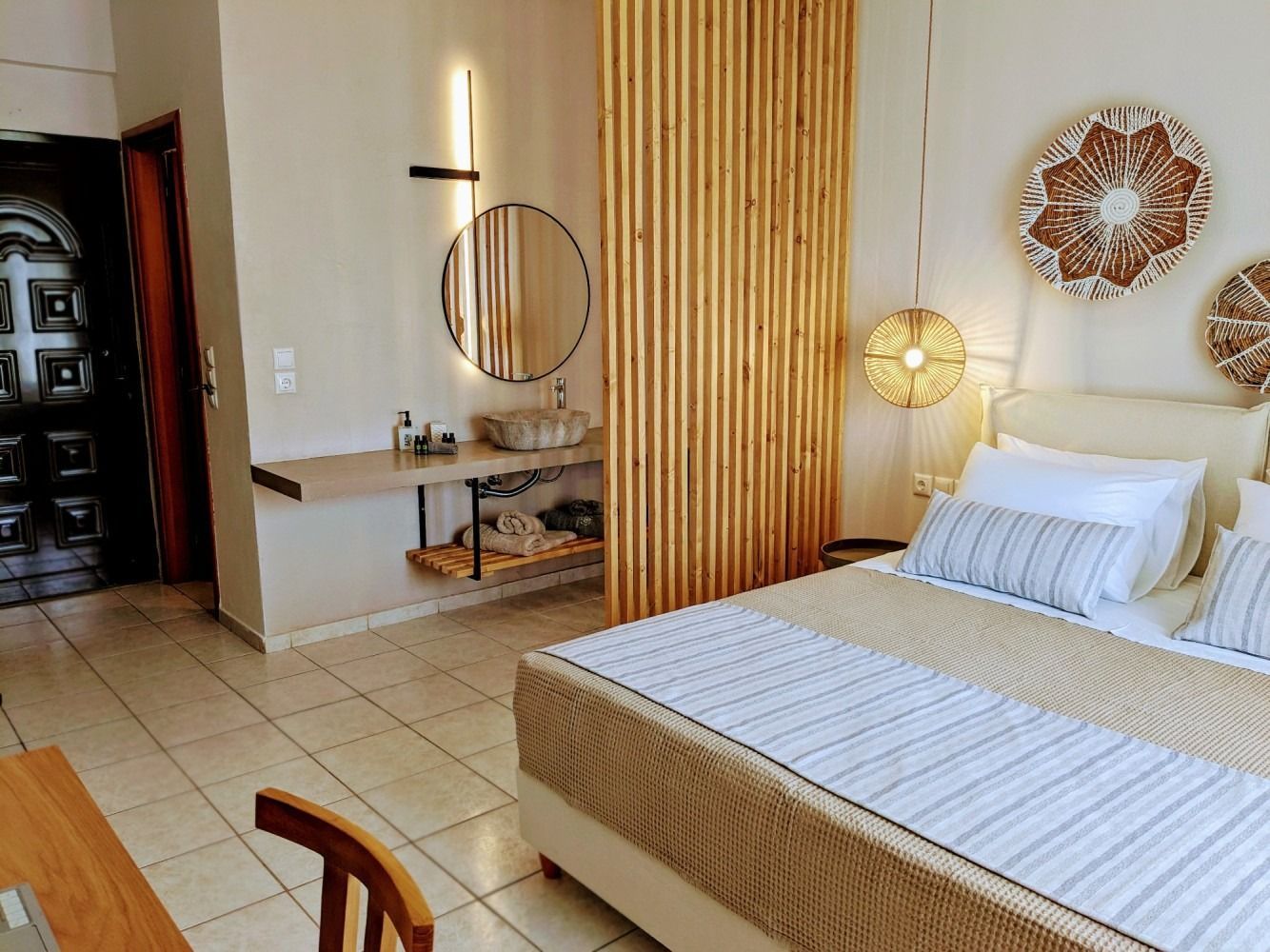 A hotel room with a bed , sink and mirror.