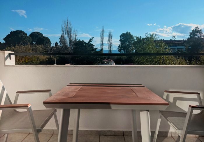 A table and chairs on a balcony with a view of the ocean.