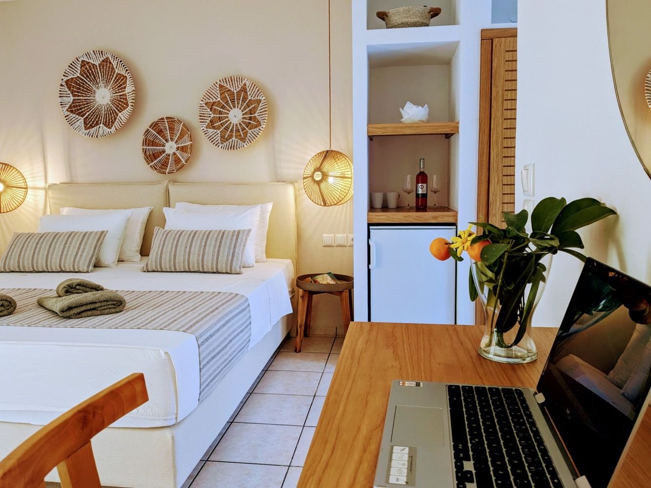 A hotel room with a large bed and a laptop on a desk.