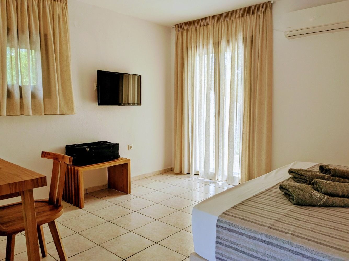 A hotel room with a bed , television , table and chairs.