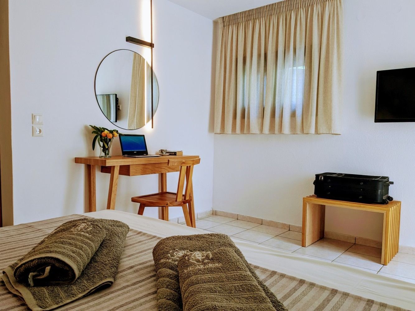 A bedroom with a bed , desk , mirror and television.