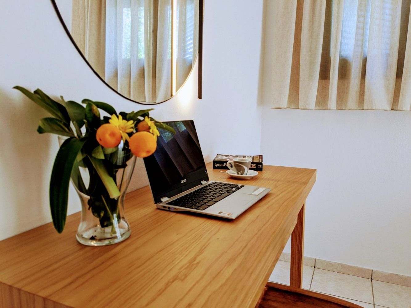 A desk with a laptop and a vase of flowers on it