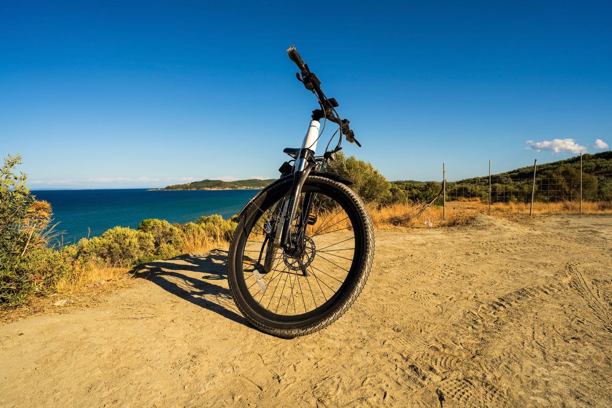 A bicycle is parked on a dirt road near the ocean.
