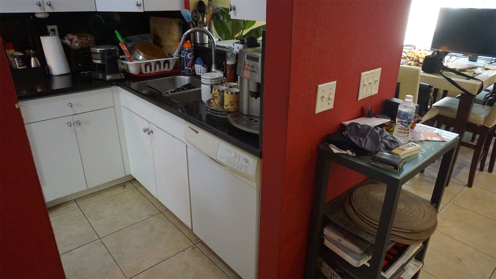 a kitchen with white cabinets and a red wall