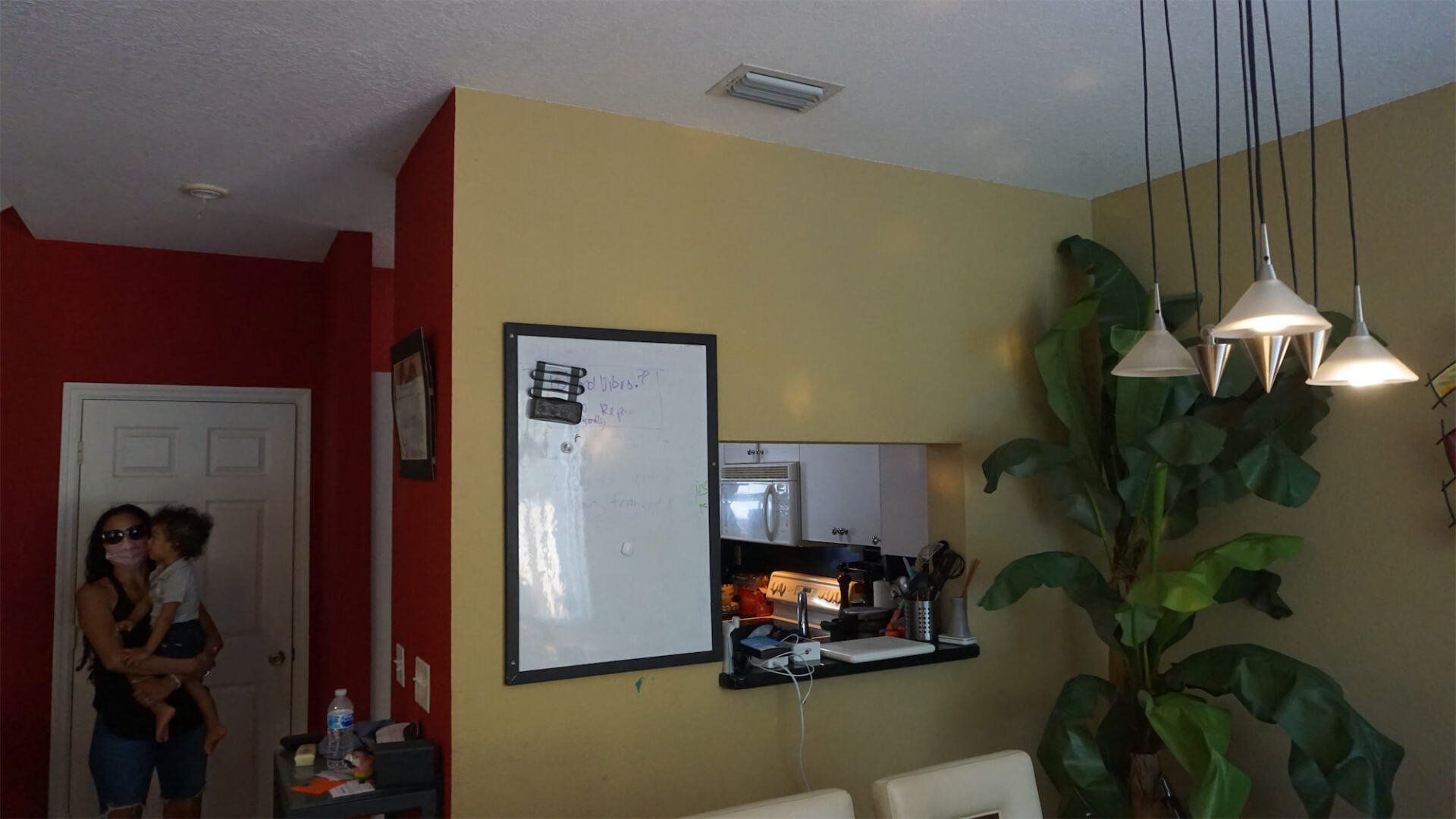 a woman holding a baby in a dining room with a white board