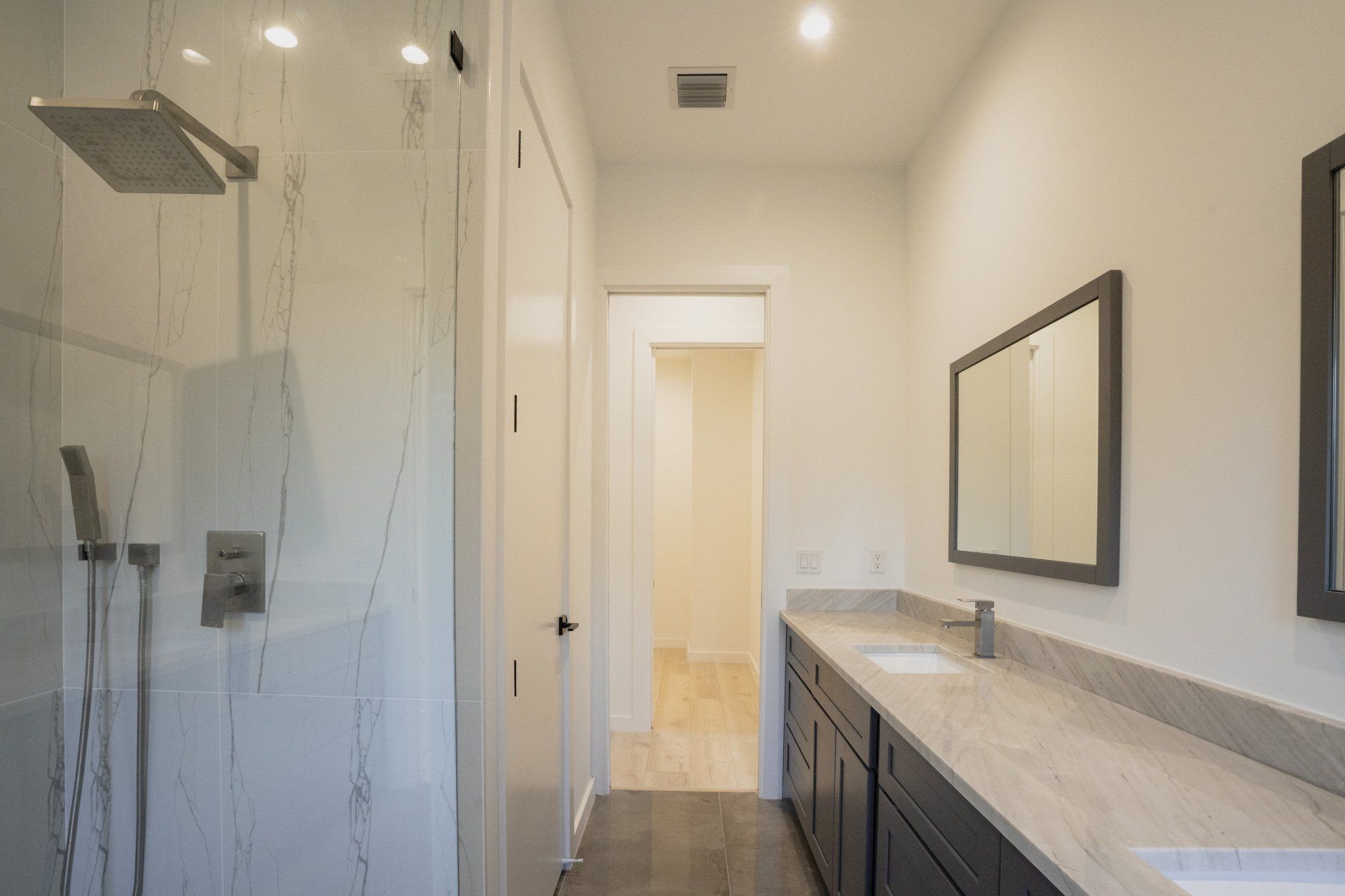 a bathroom with a walk in shower , sink and mirror .