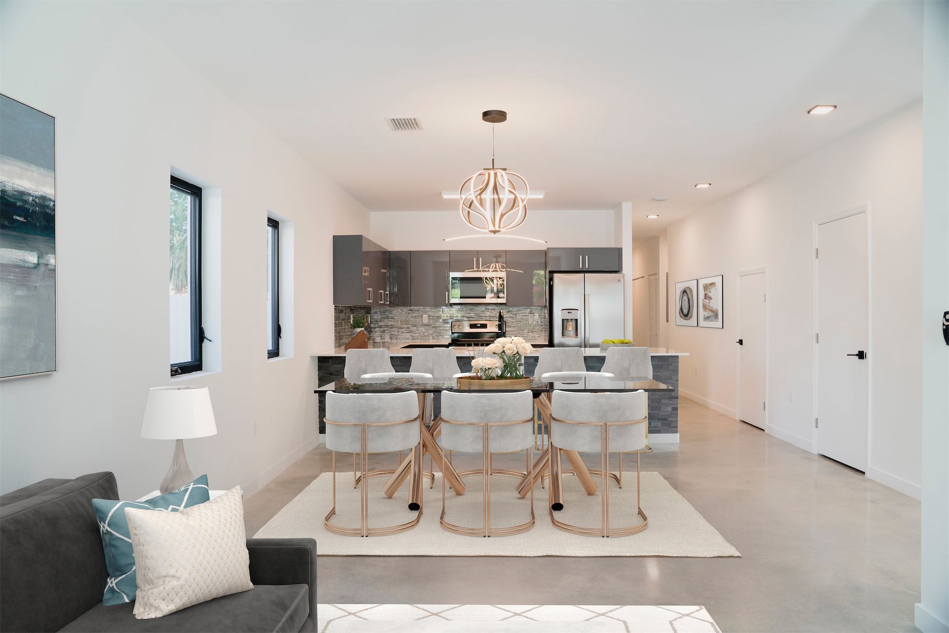 a living room with a couch , table and chairs and a kitchen .