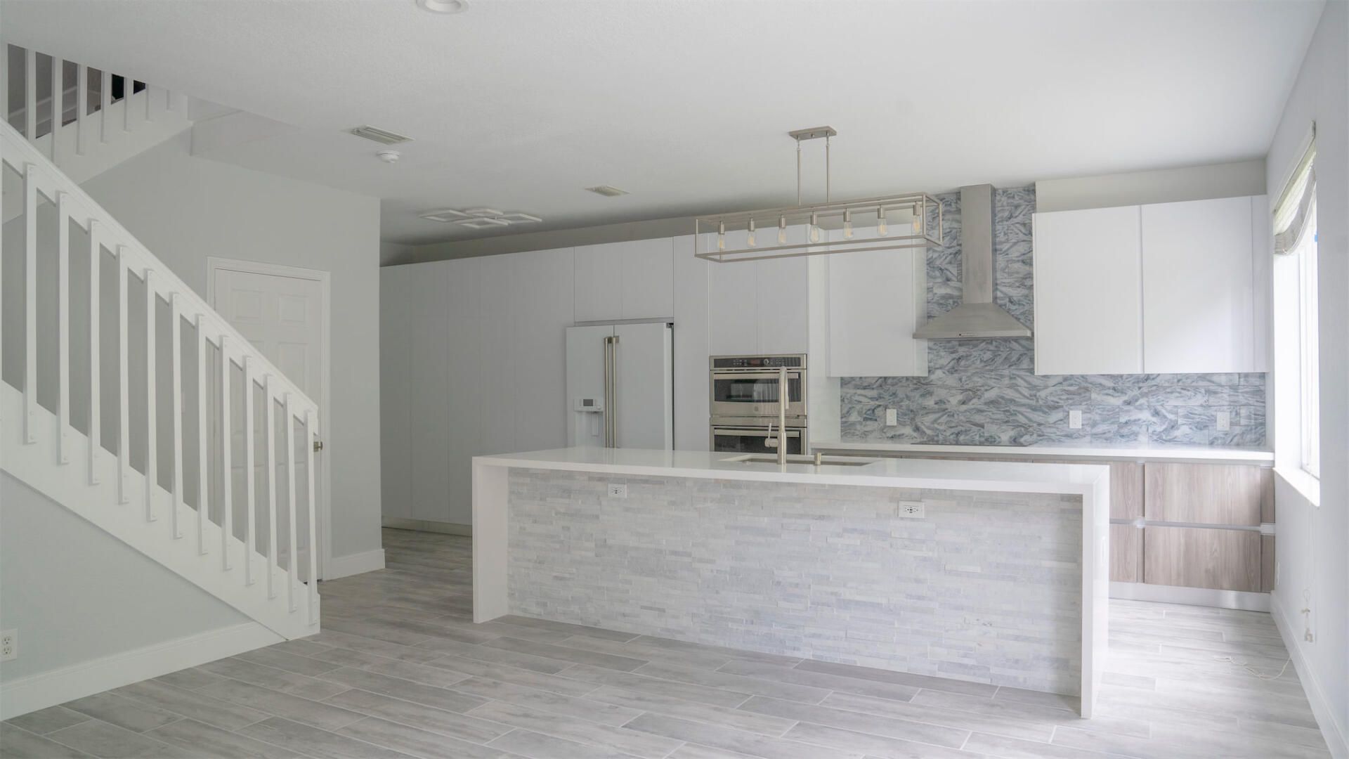 an empty kitchen with a staircase leading up to the second floor .