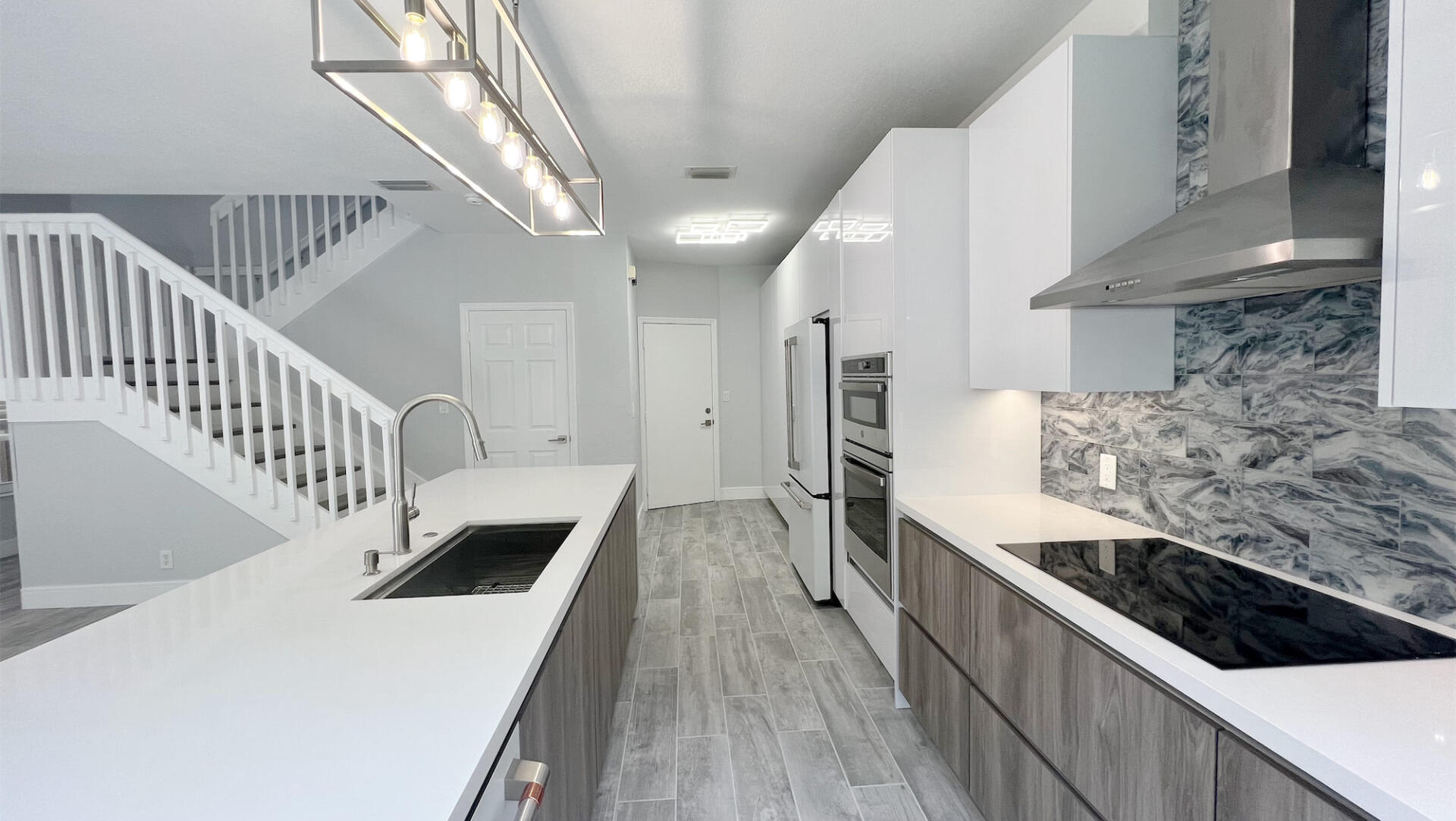 a kitchen with a sink , stove , refrigerator , and stairs .
