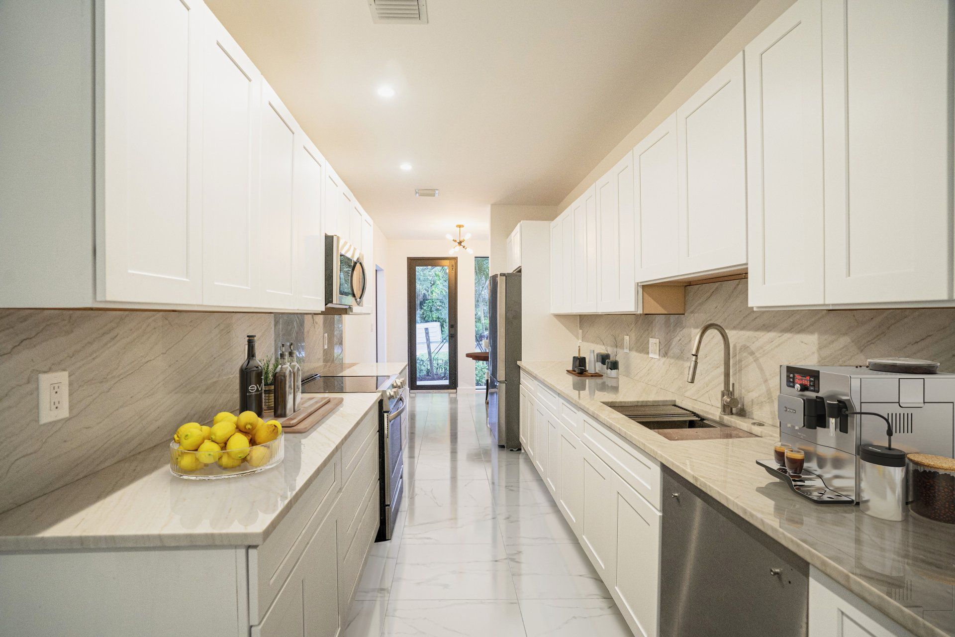 a long kitchen with white cabinets and stainless steel appliances .