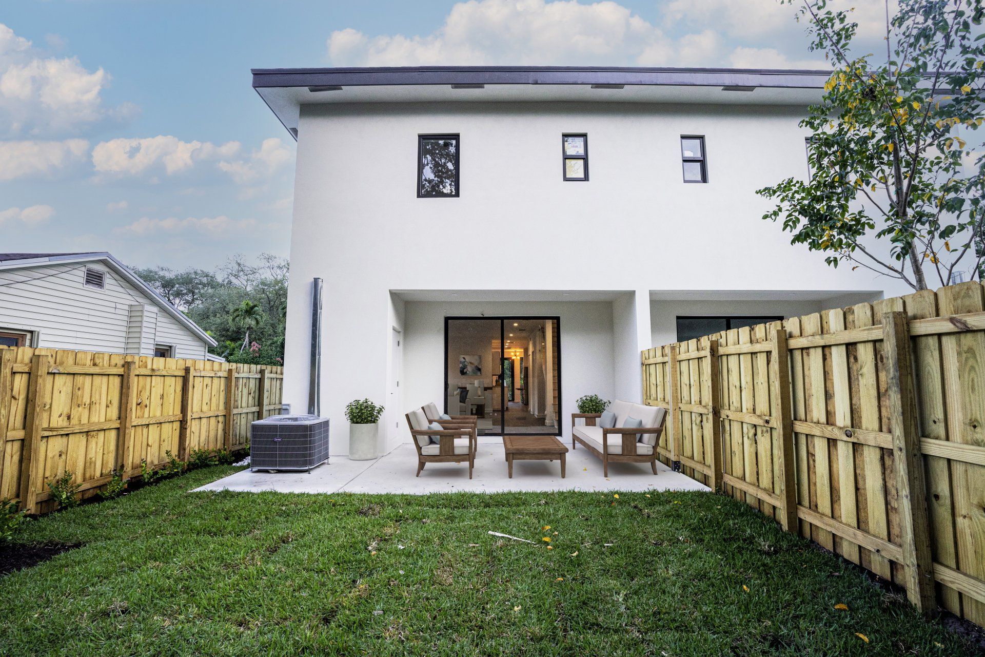 the backyard of a white house with a wooden fence and patio .