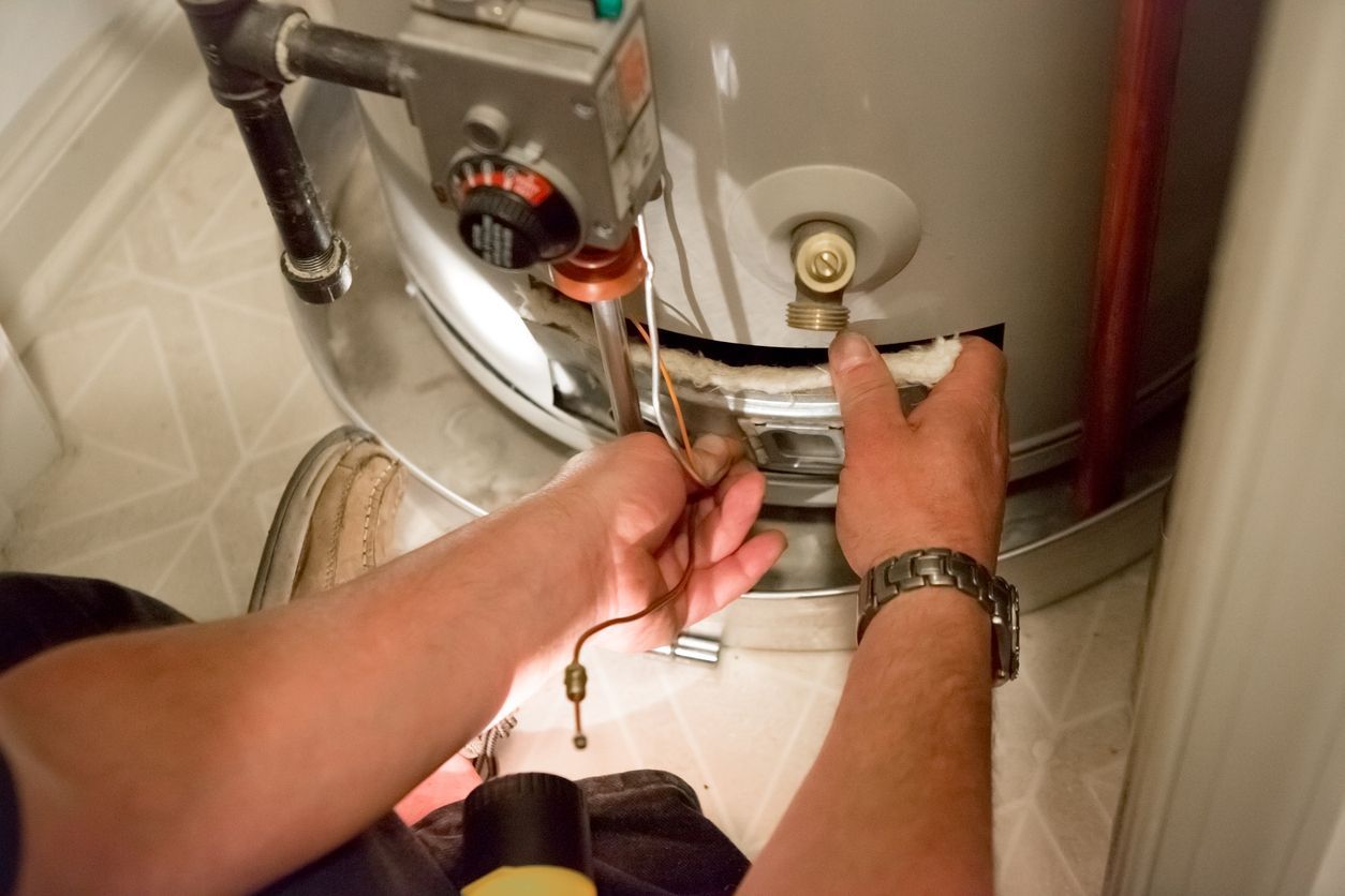 Person repairing a gas water heater, near the control panel.