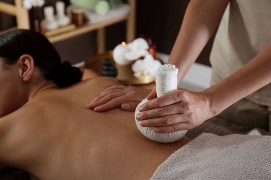 Mani in gesto di massaggio ayurvedico con oli caldi