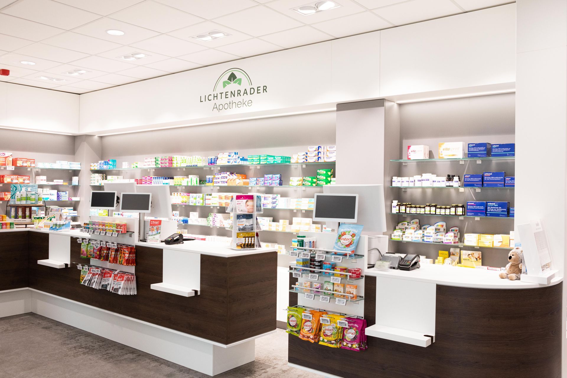 Innenansicht einer Apotheke mit Medikamentenregalen hinter den Kassen; Schild über der Theke.