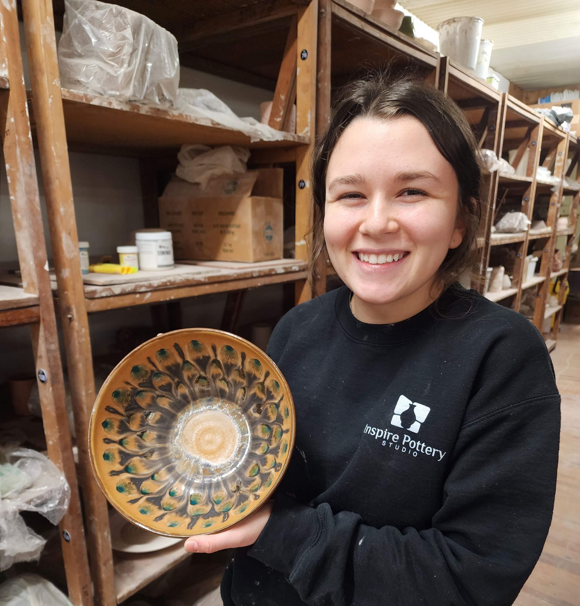 a woman in a black sweater is holding a plate and smiling