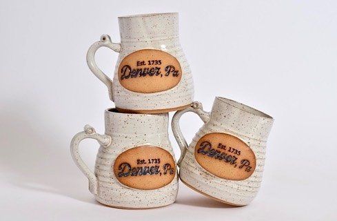 three mugs are stacked on top of each other on a white surface .