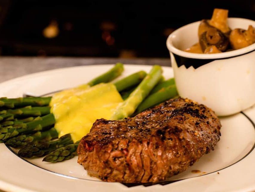 a white plate topped with a steak asparagus and mashed potatoes