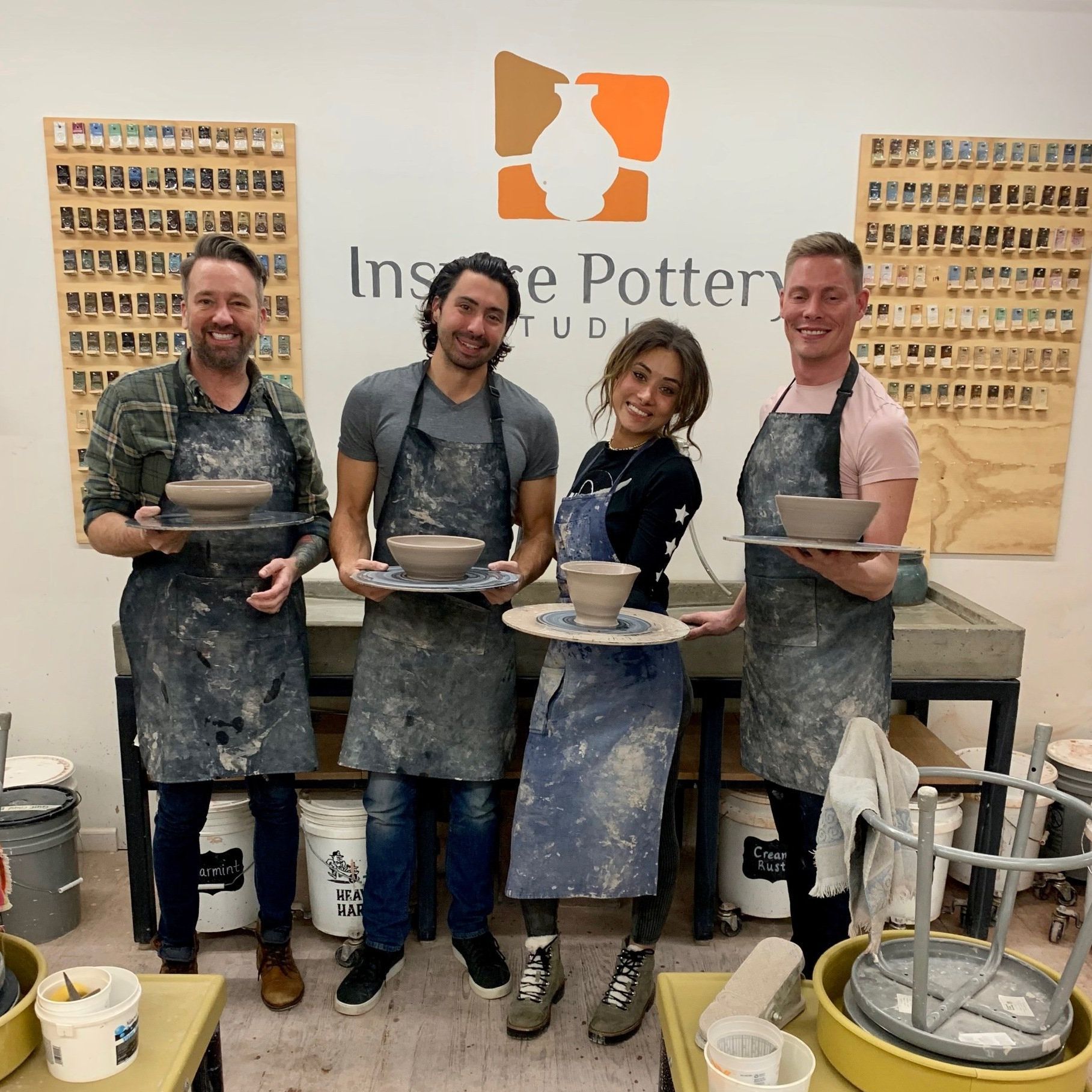 a group of people standing in front of a sign that says pottery