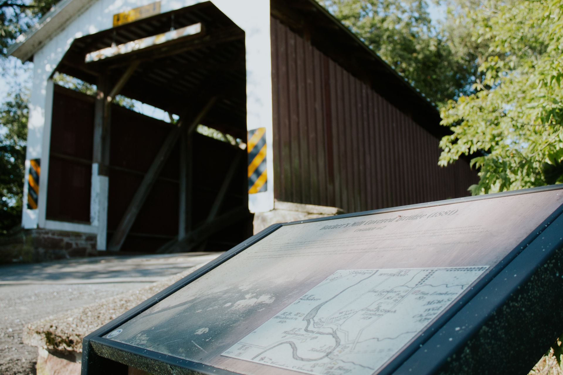 a sign in front of a covered bridge with a map on it .