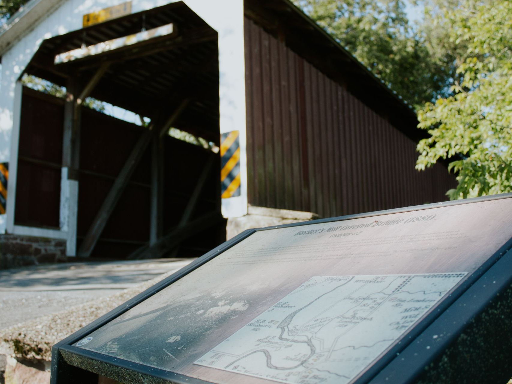 Bridge with a map a covered bridge with a sign in front of it