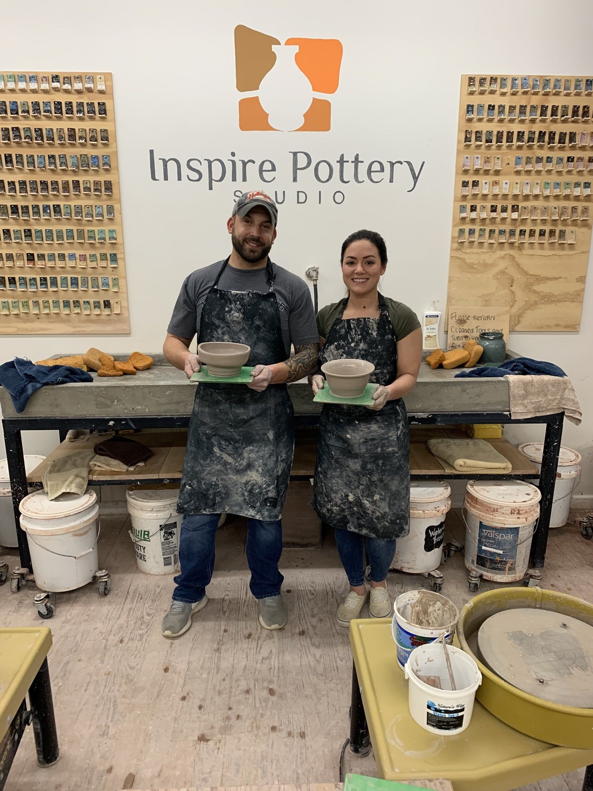 A man and a woman are standing next to each other in a pottery studio.