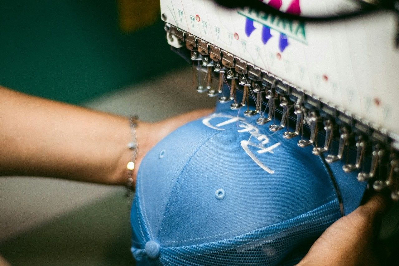 Close-up of a sewing machine stitching white thread on brown woven fabric