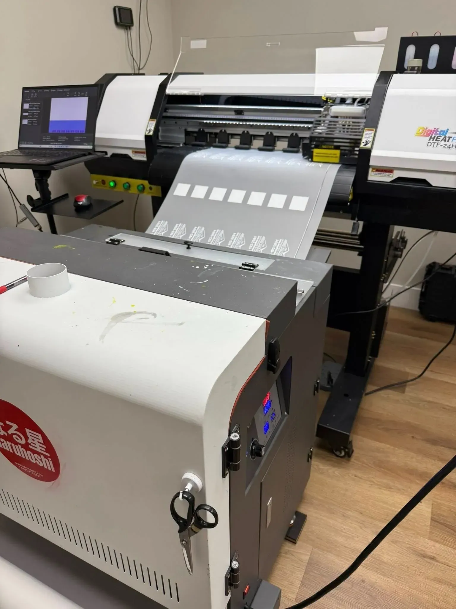 Large-format printer in a workshop feeding sheets of printed paper onto a tray