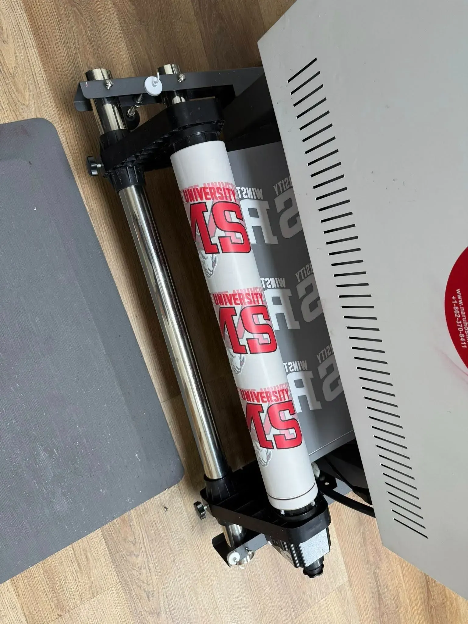 White and gray gas cylinder secured in a black metal mount beside a vented cabinet panel