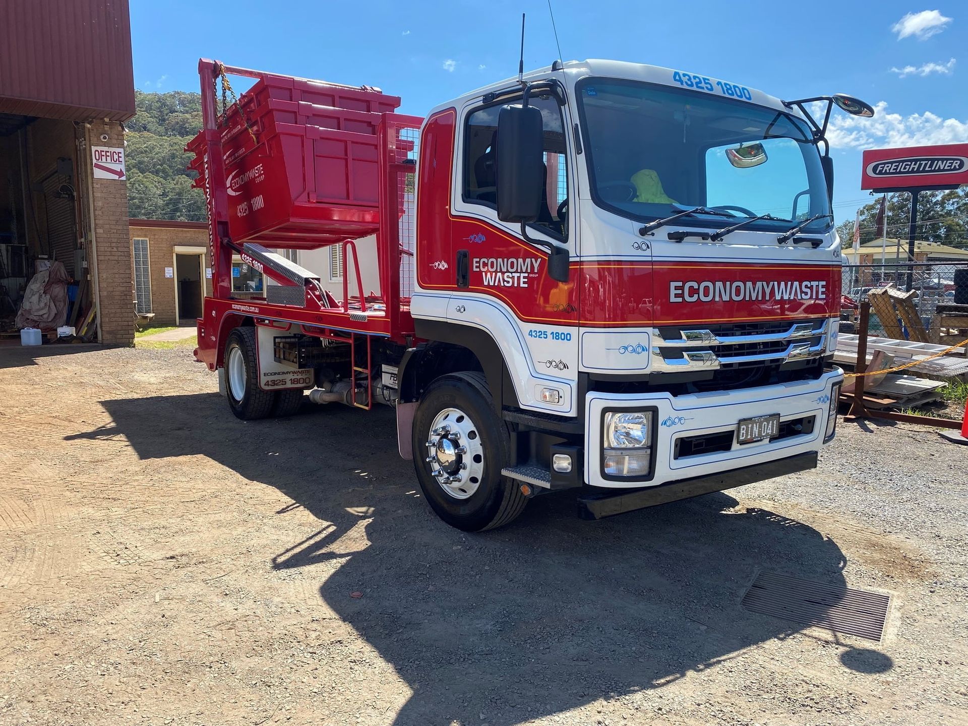 A Red and White Garbage Truck Parked Outside — Economy Waste Group | Skip Bins Central Coast In Bateau Bay, NSW