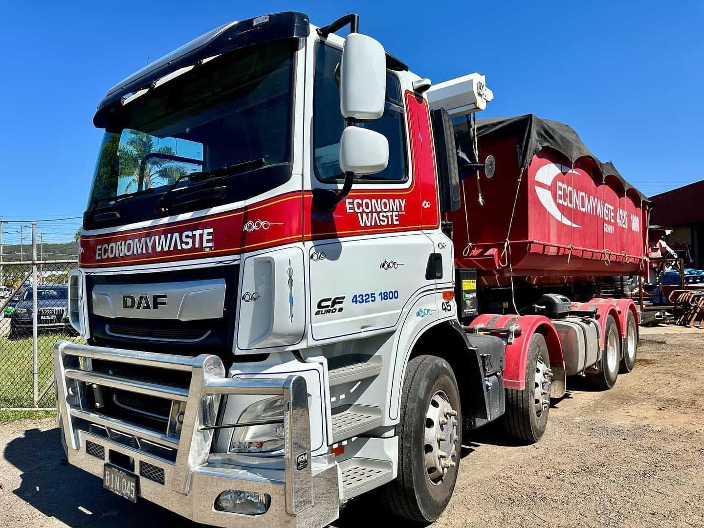 A Red and White Economy Waste Truck With a Dumpster — Economy Waste Group | Skip Bins Central Coast In West Gosford, NSW
