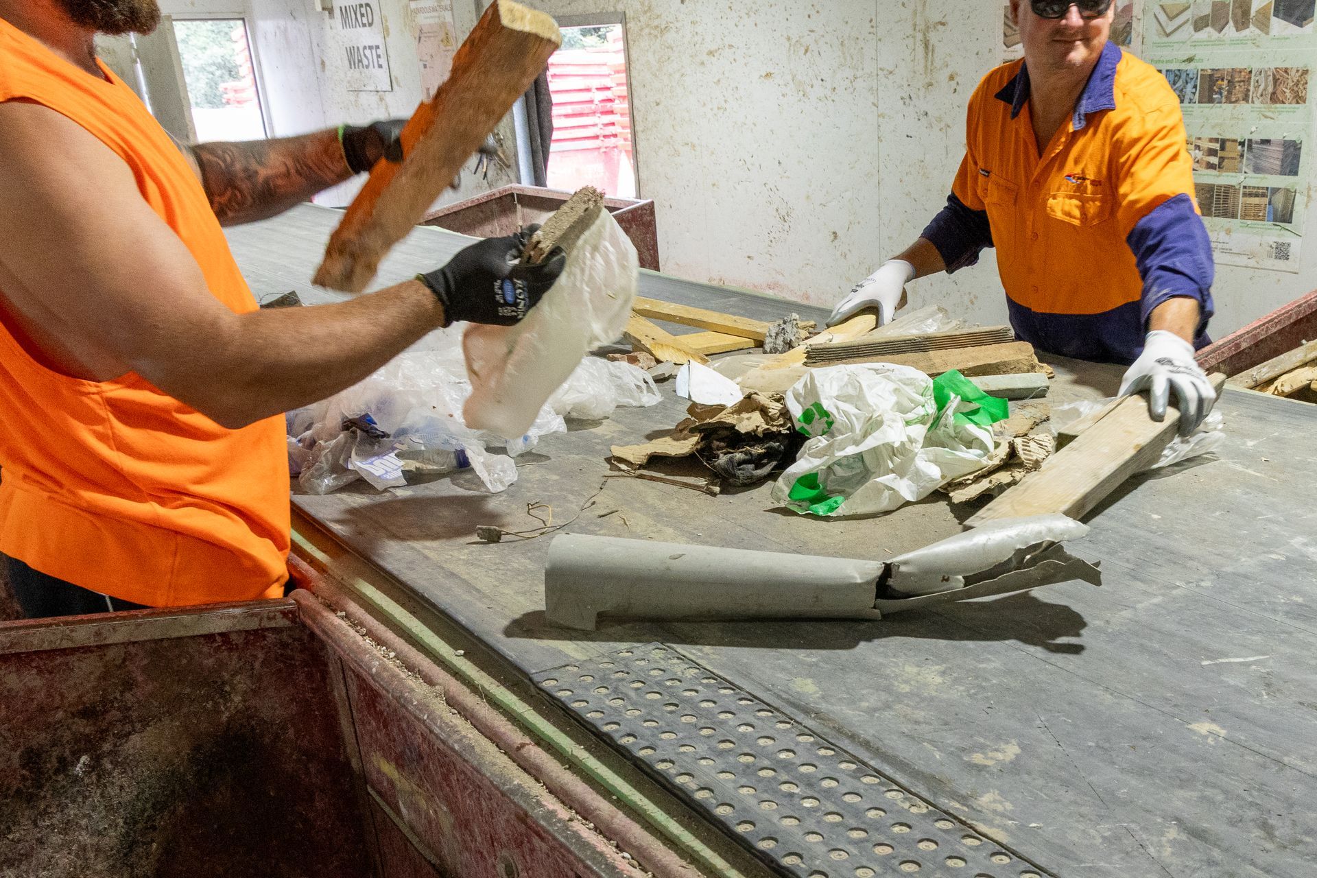 Two Workers in Orange Sorting Waste on a Conveyor Belt — Economy Waste Group | Skip Bins Central Coast In Kincumber, NSW