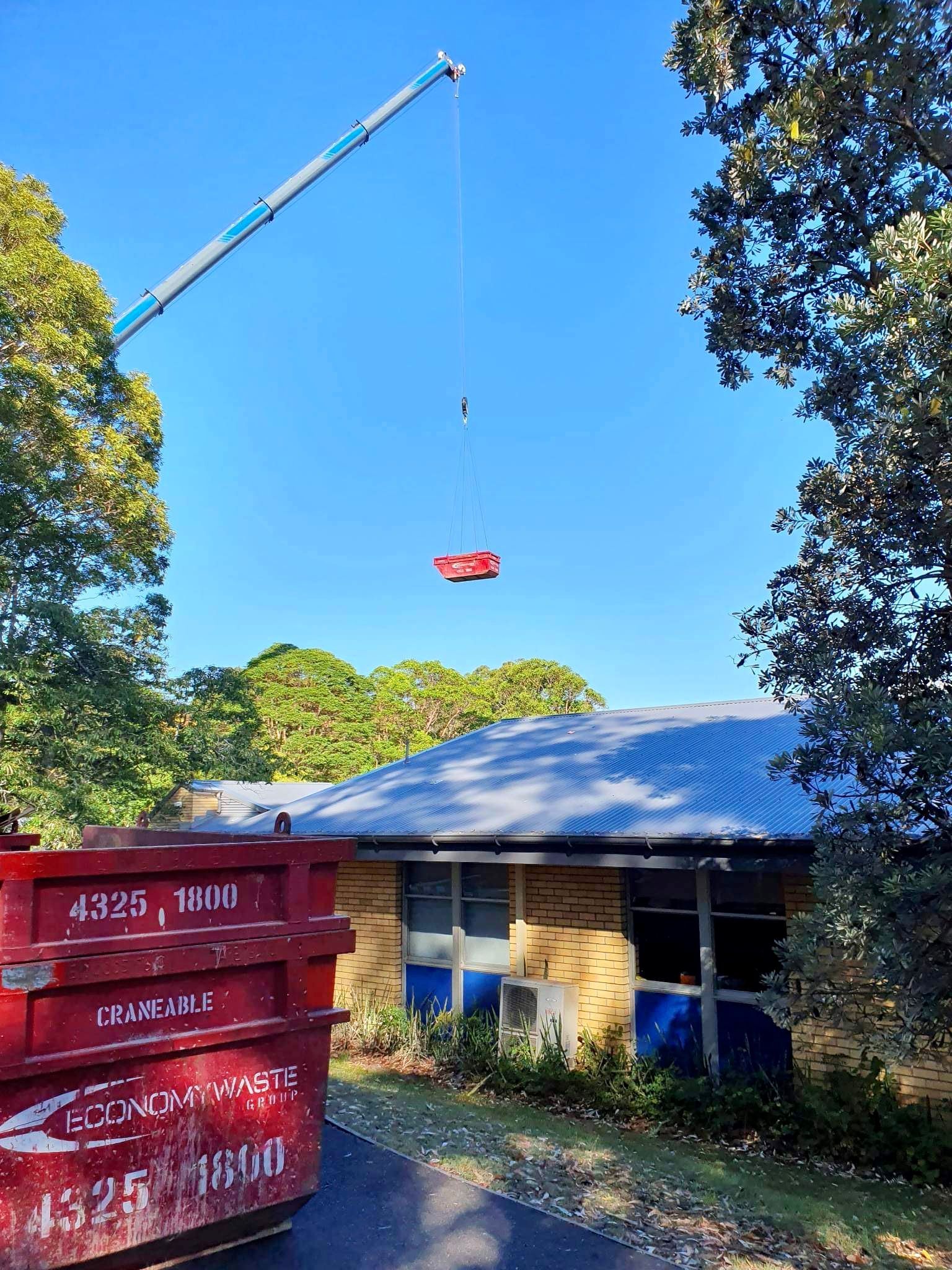 A Crane Lifts a Red Container — Economy Waste Group | Skip Bins Central Coast In Terrigal, NSW