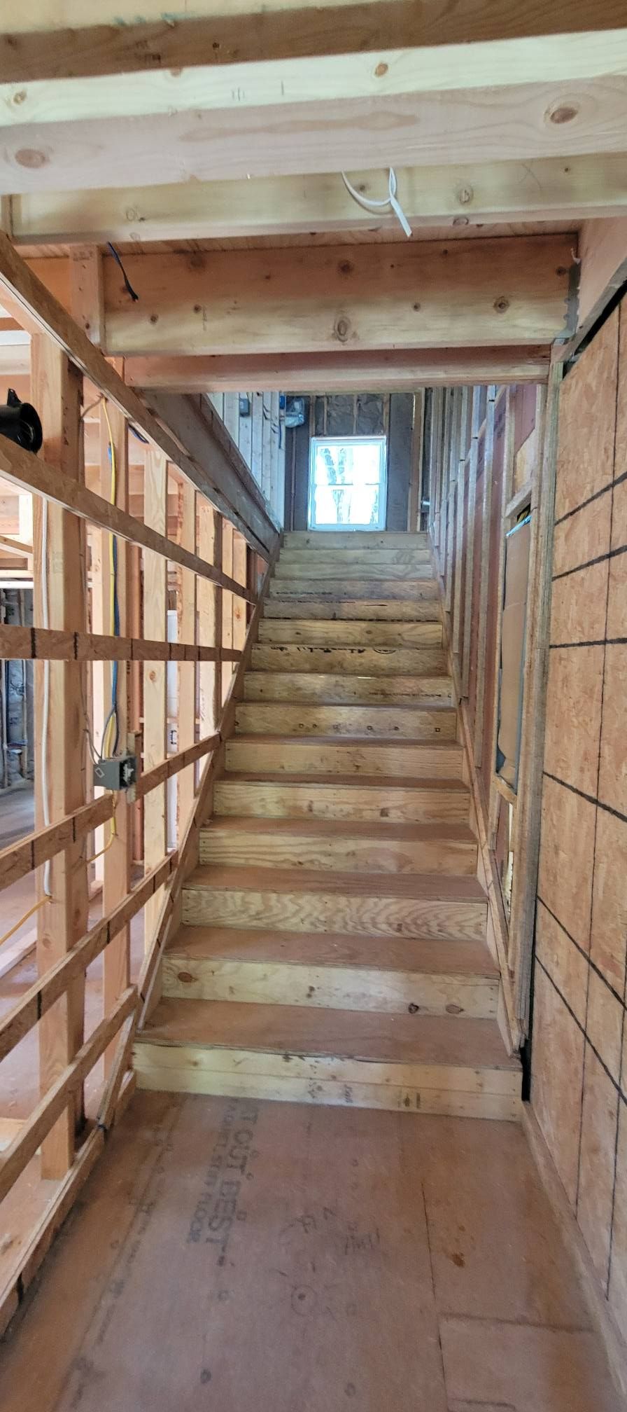 Wooden staircase in a home under construction, leading up.