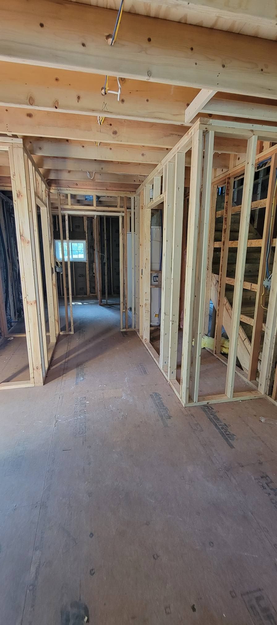 Interior view of a building under construction. Wooden framework, exposed ceiling beams, and unfinished floor.