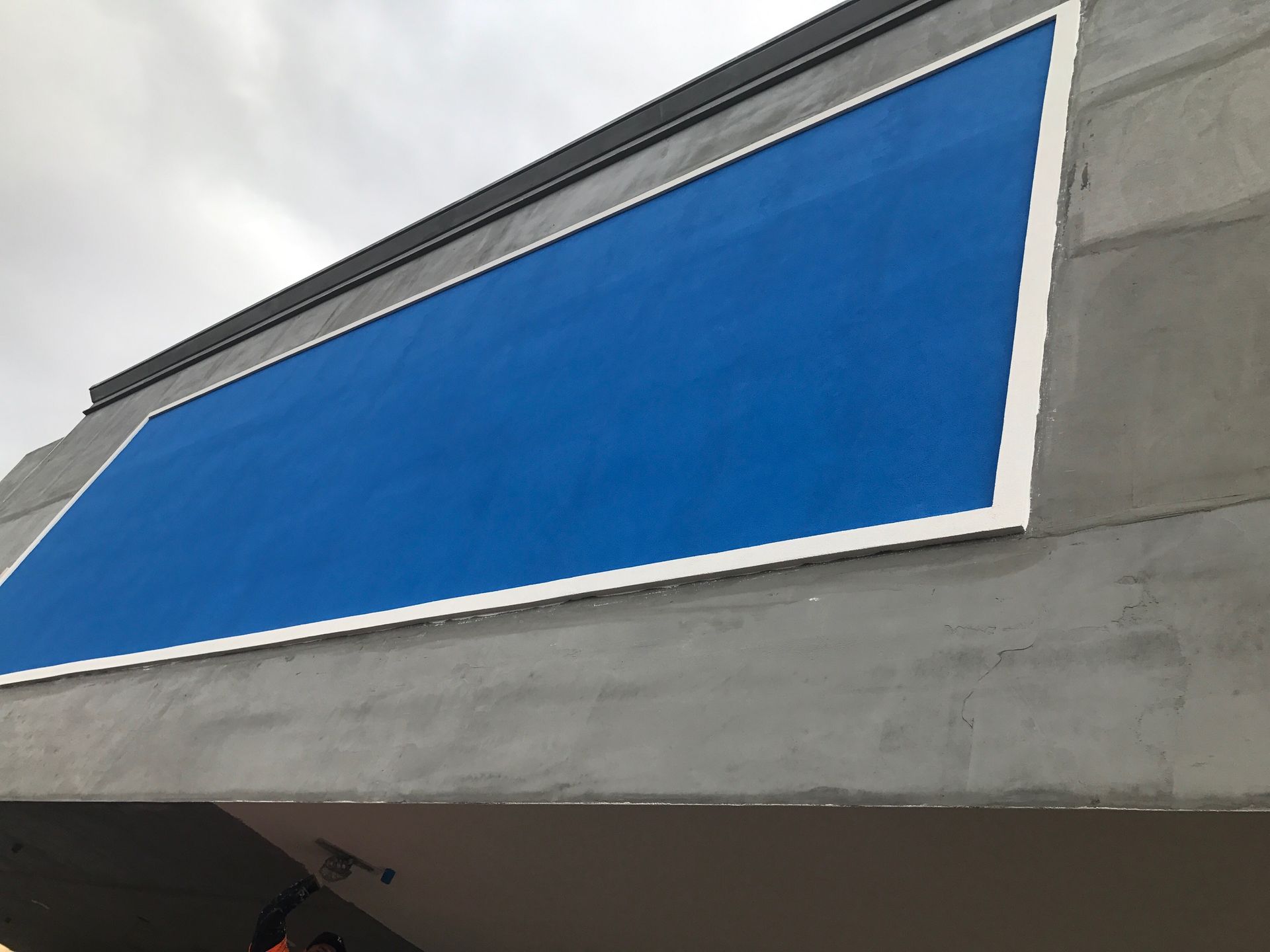Blue panel set in white frame on a gray concrete building.