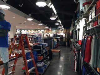 Clothing store interior with clothing racks, shelves, mannequins, and ladder.