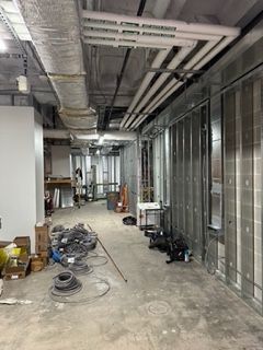 Interior hallway under construction; metal studs, pipes, and wires exposed.