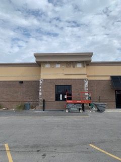 Exterior of building undergoing construction; brick and beige exterior with a lift.