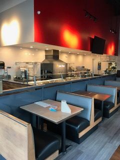 Restaurant interior with booths and serving counter against a red and white wall.